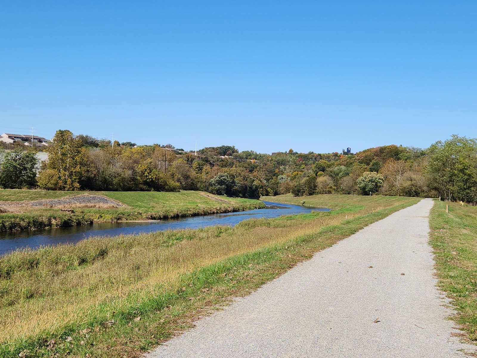 people walking a paved riverside trail on a sunny fall morning / golden autumn sunrise over a small Southern river town / family in light jackets outdoors on a warm fall afternoon