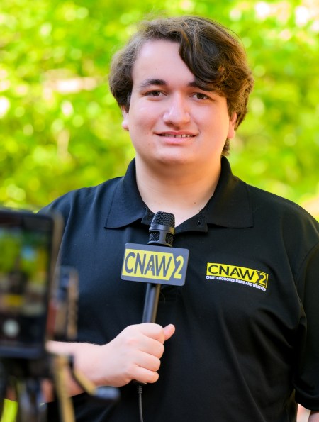 Colin Scroggins, the lead reporter at CNAW 2 News, holding a microphone