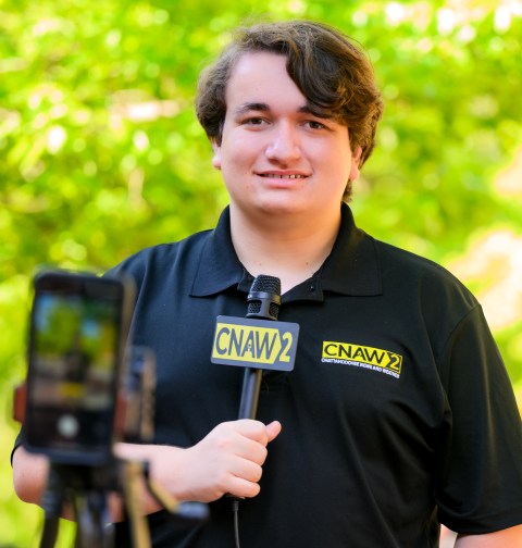 Colin Scroggins, the lead reporter at CNAW 2 News, holding a microphone